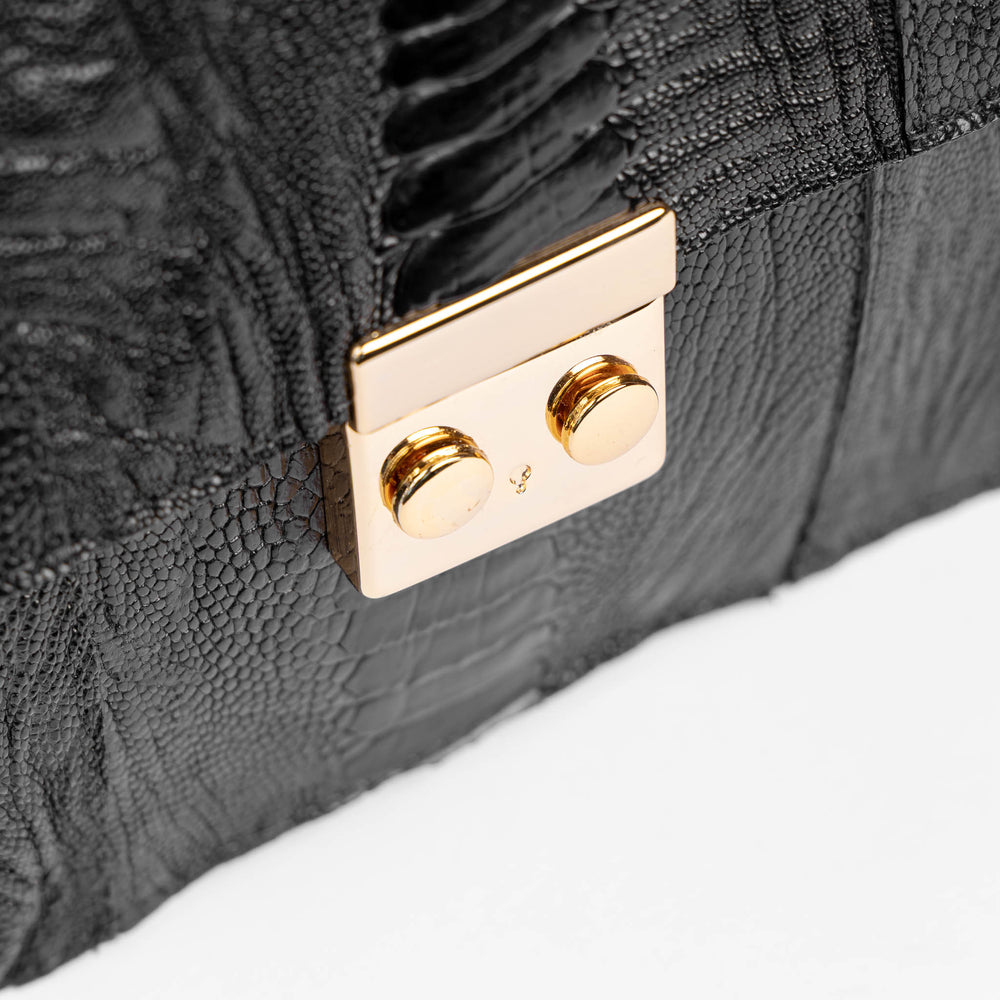 Detalhe do fecho push-lock em metal dourado da bolsa baguete Strut em canela de avestruz