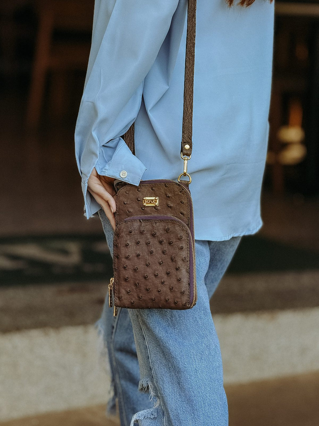 Detalhe da mini bolsa carteira Strut em couro de avestruz cheio caramelo com alça transversal