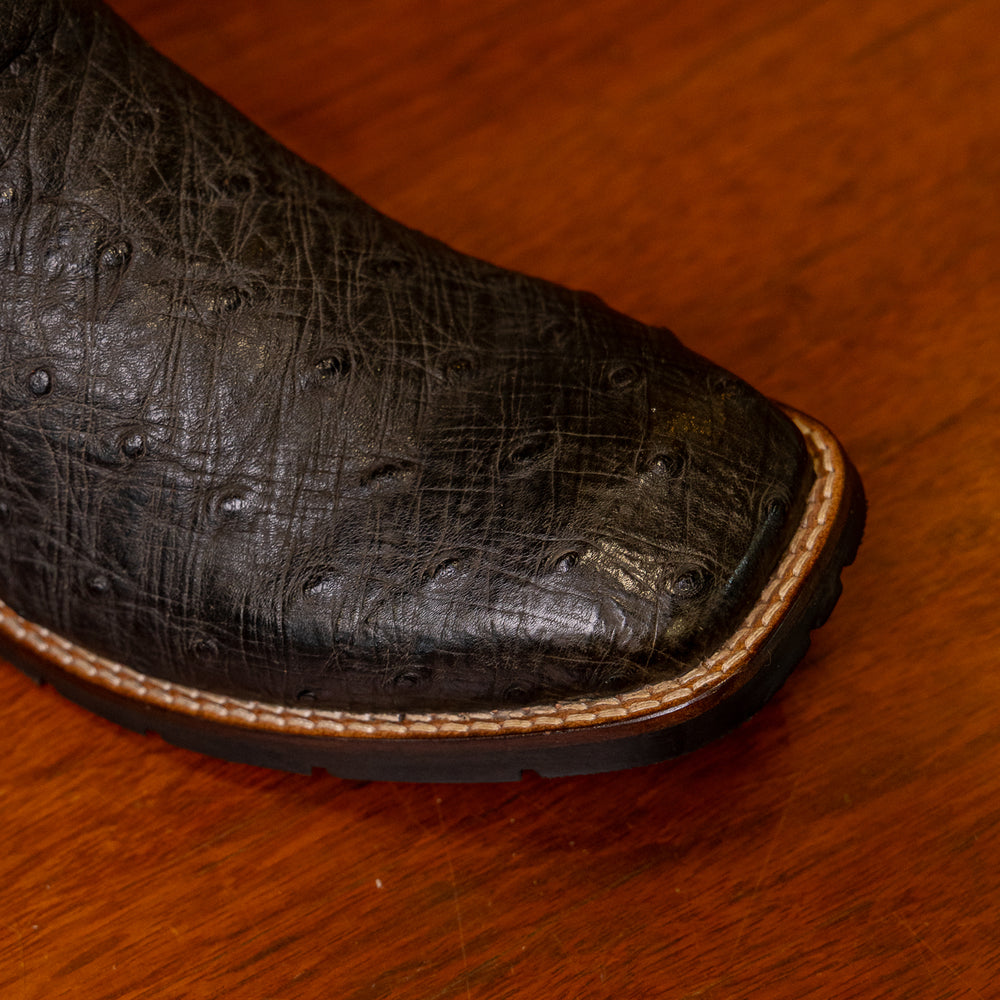 Detalhe do bico da bota masculina strut em couro de avestruz cheio preto com cano preto bordado vermelho e branco