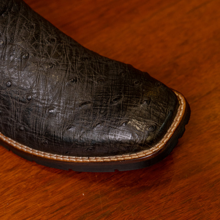 Detalhe do bico da bota masculina strut em couro de avestruz cheio preto com cano preto bordado vermelho e branco