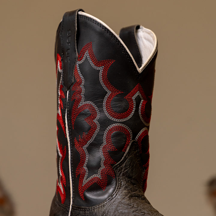 Detalhe do cano da bota masculina strut em couro de avestruz cheio preto com cano preto bordado vermelho e branco