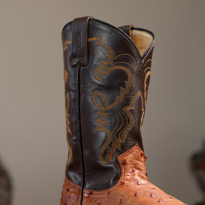 Detalhe do cano da bota masculina strut em couro de avestruz cheio chestnut com cano marrom-escuro bordado laranja e bege