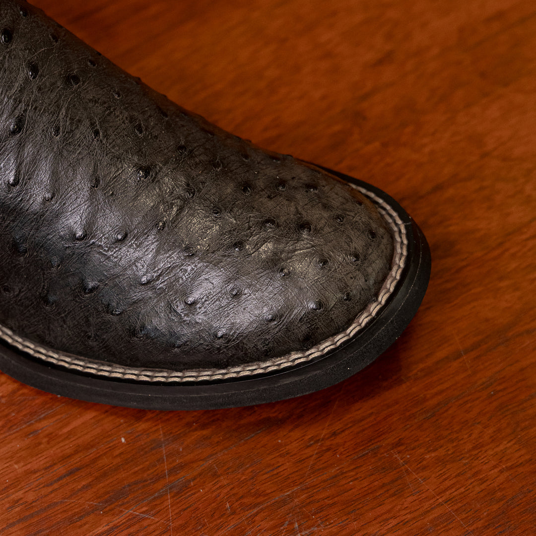 Detalhe do bico redondo da bota masculina strut em couro de avestruz cheio preto com cano preto bordado azul