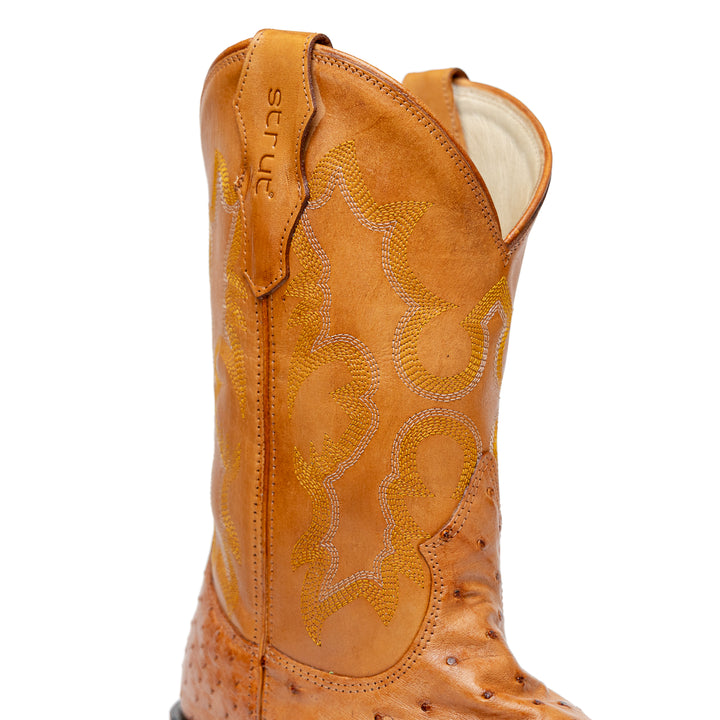 Detalhe do cano da bota masculina strut em couro de avestruz cheio chestnut com cano caramelo bordado amarelo