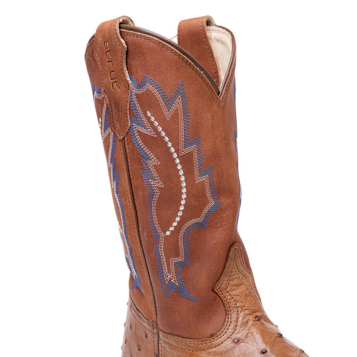 Detalhe do cano da bota masculina strut em couro de avestruz cheio tabaco com cano caramelo bordado azul e bege